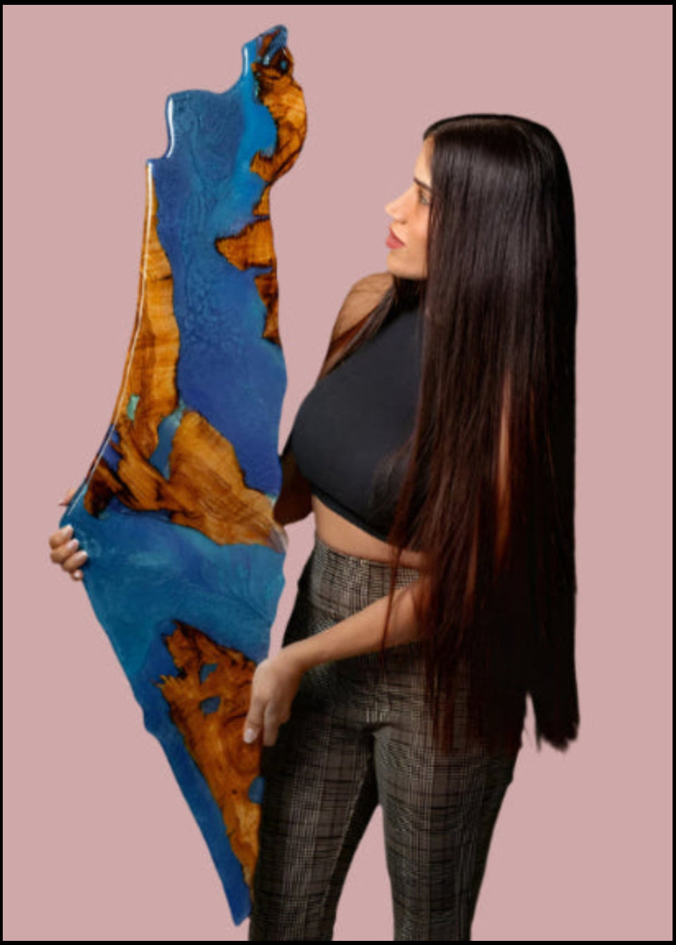 Artist holding a large, abstract art piece with blue and brown colors against a gray background